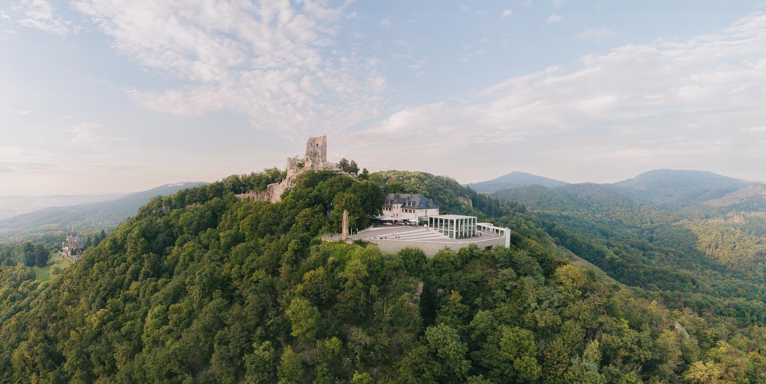 Luftaufnahme der historischen Burgruine Drachenfels umgeben von den grünen Wäldern des Siebengebirges.