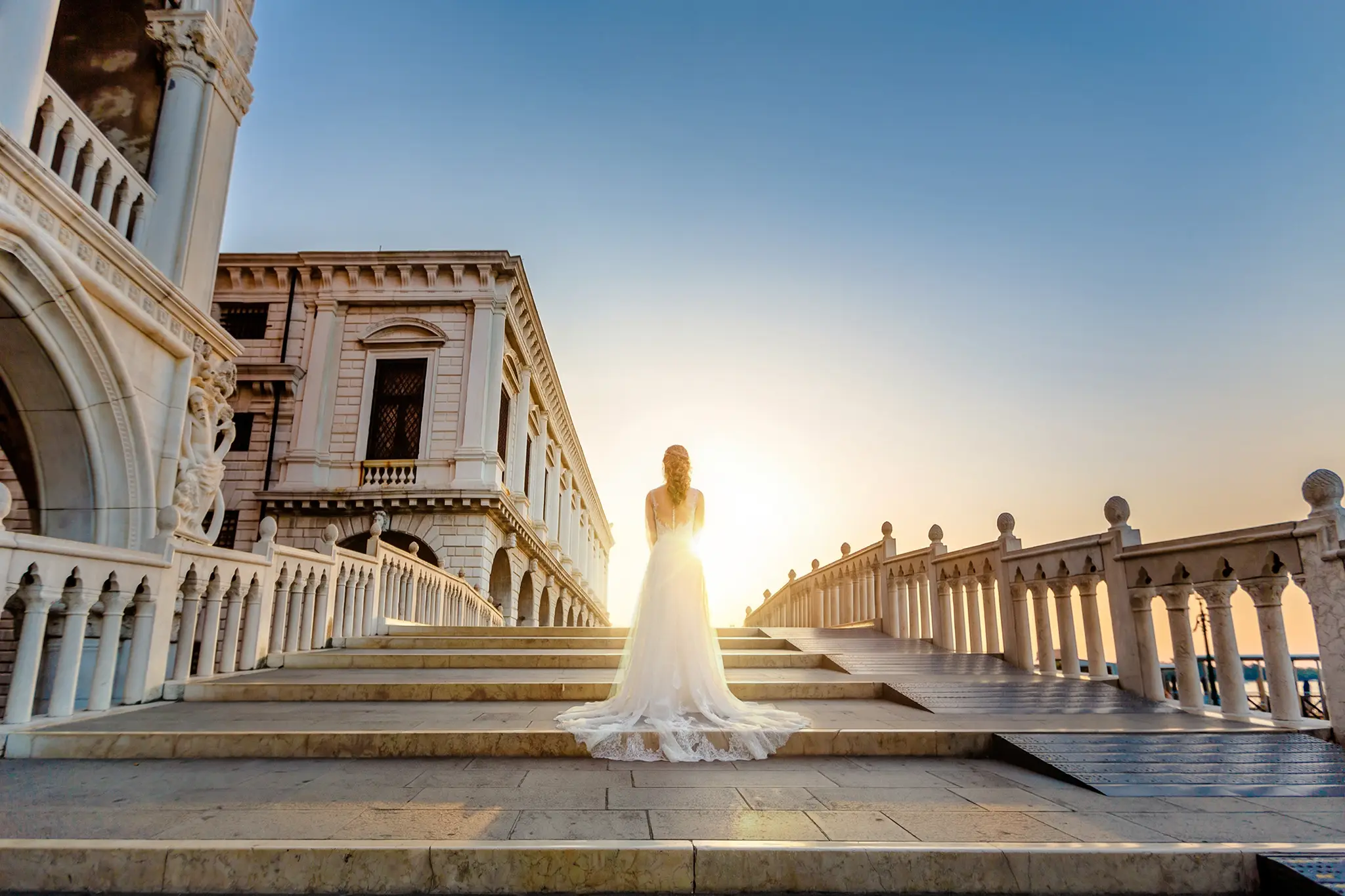 HOCHZEITSFOTOGRAF VENEDIG 43 Dramatische Silhouette einer Braut im Hochzeitskleid auf einer venezianischen Brücke, während die ersten Sonnenstrahlen durch die historische Architektur brechen.