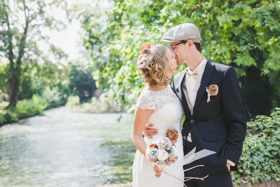 Brautpaar mit Vintage Style küsst sich am Wasser