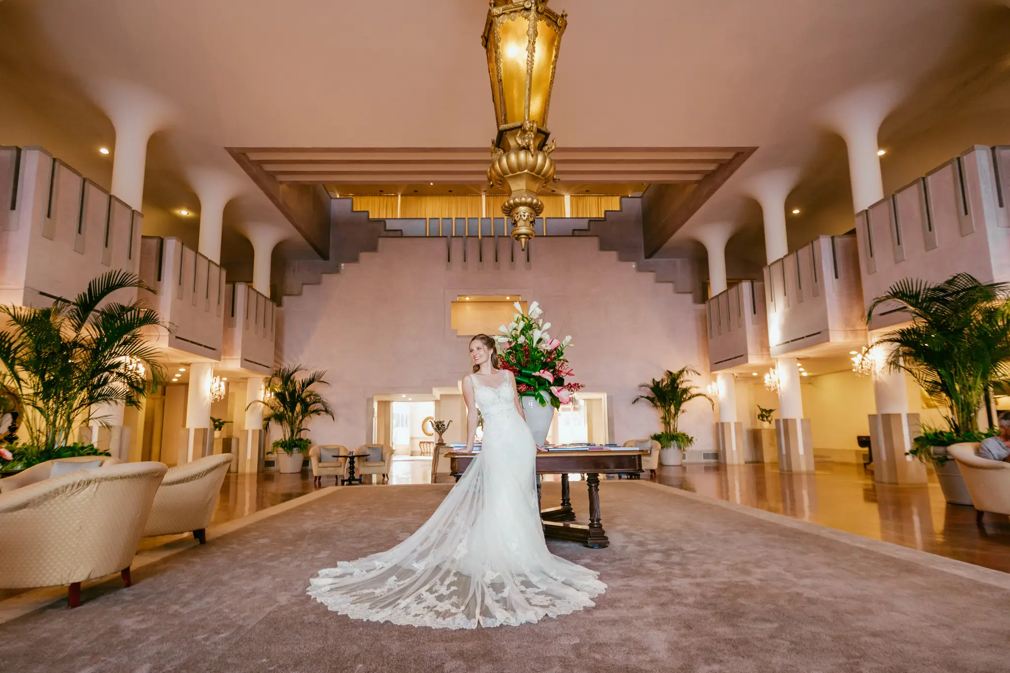 HOCHZEITSFOTOGRAF VENEDIG 59 Braut mit langer Spitzenschleppe in der historischen Lobby des Hotel Excelsior Venice Lido. Destination Wedding Fotografie an einer der ikonischsten Hochzeitslocations Venedigs.