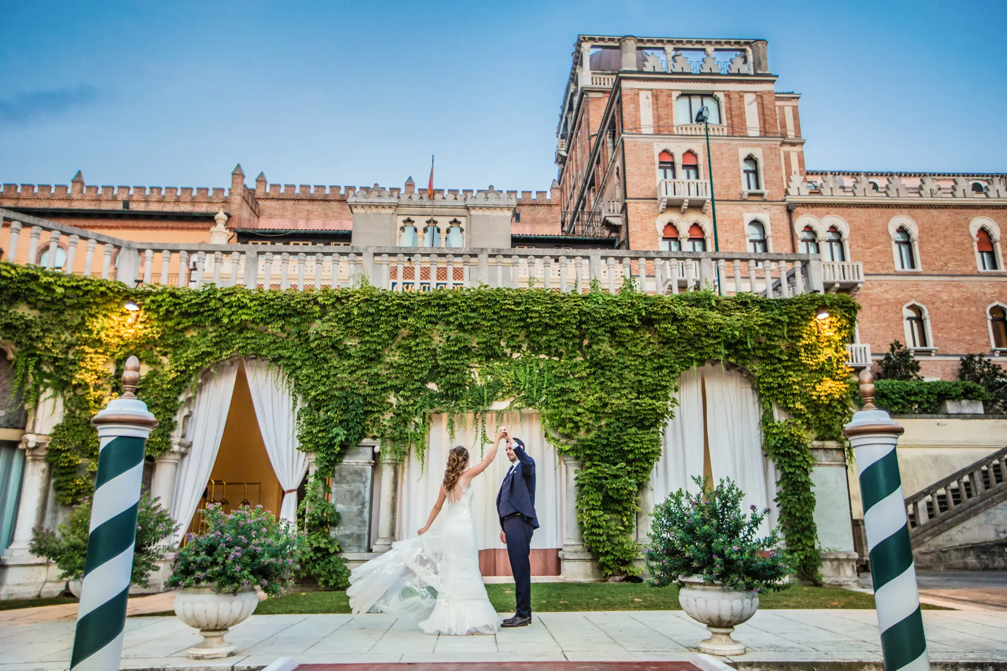 HOCHZEITSFOTOGRAF VENEDIG 60 Bräutigam dreht seine Braut unter einer Efeuumrankten Pergola am Bootssteg des Hotel Excelsior Venice Lido. Verspieltes Tanzen beim Destination Wedding Shooting.