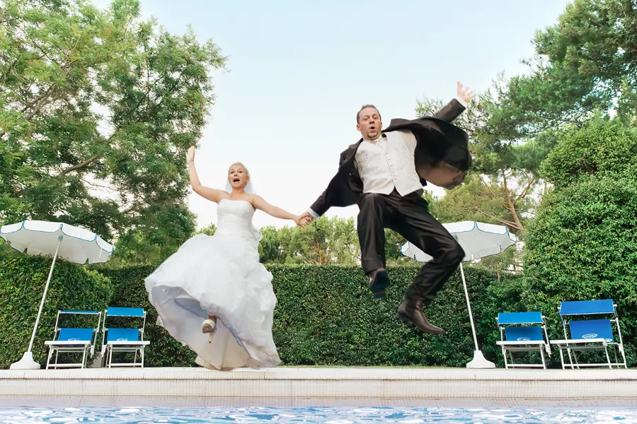 Brautpaar springt in den Hotel Pool